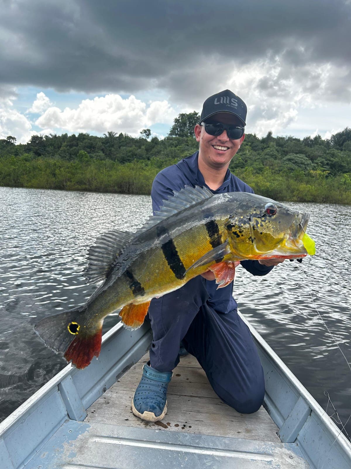 Pescador e tucunaré em registro no barco